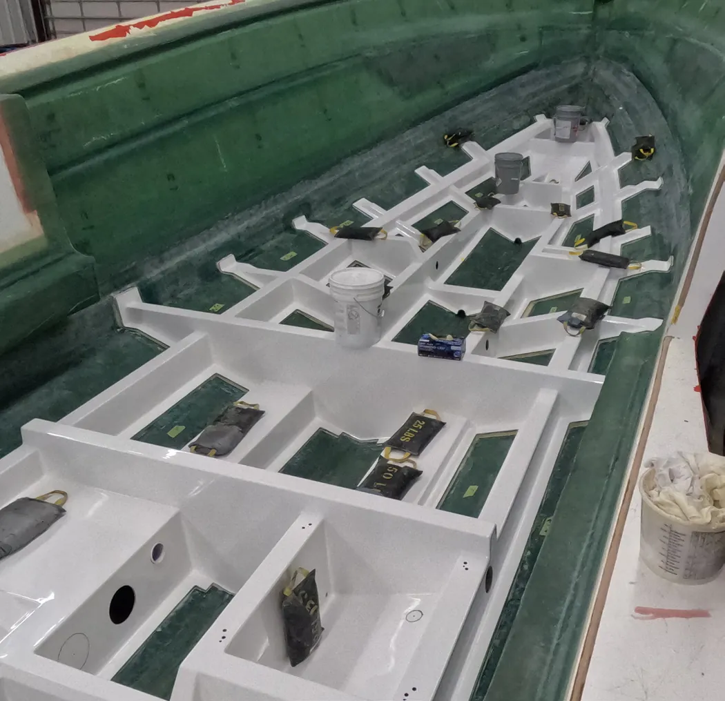 A molded structural grid being set into a hull mold