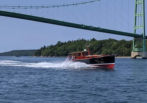 Red launch running beneath a suspension bridge
